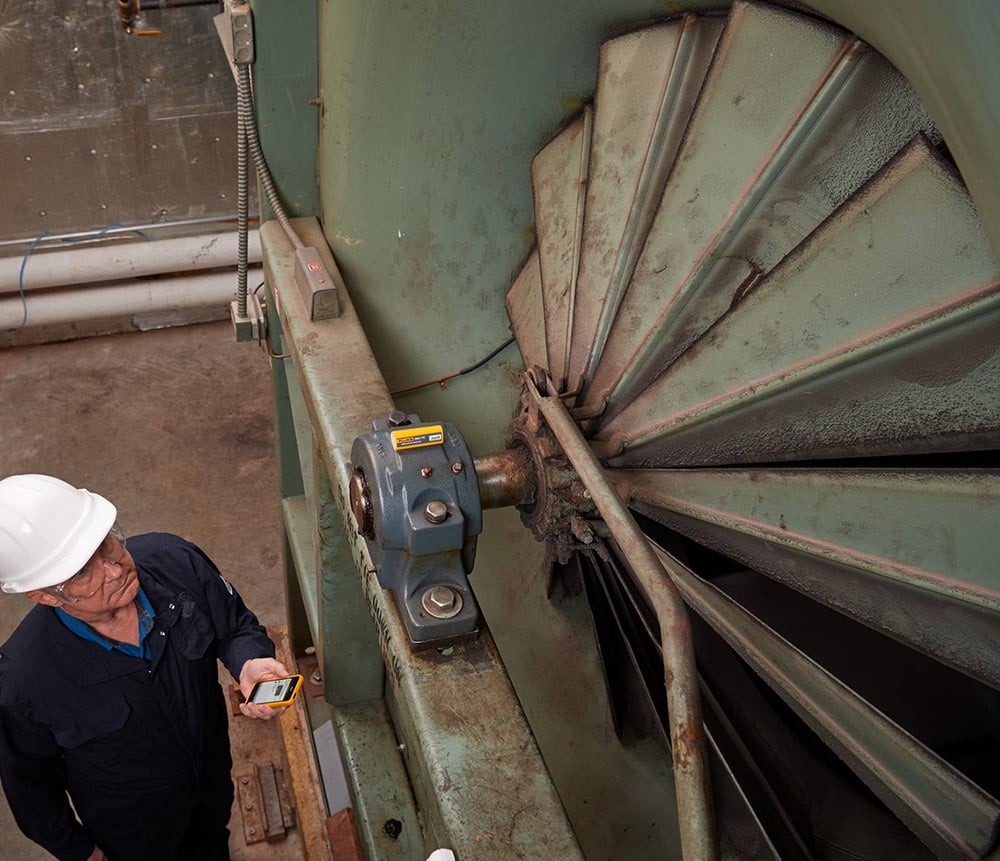 An engineer looks at a Fluke 3561 FC Vibration Sensor installed in a hard-to-reach location.