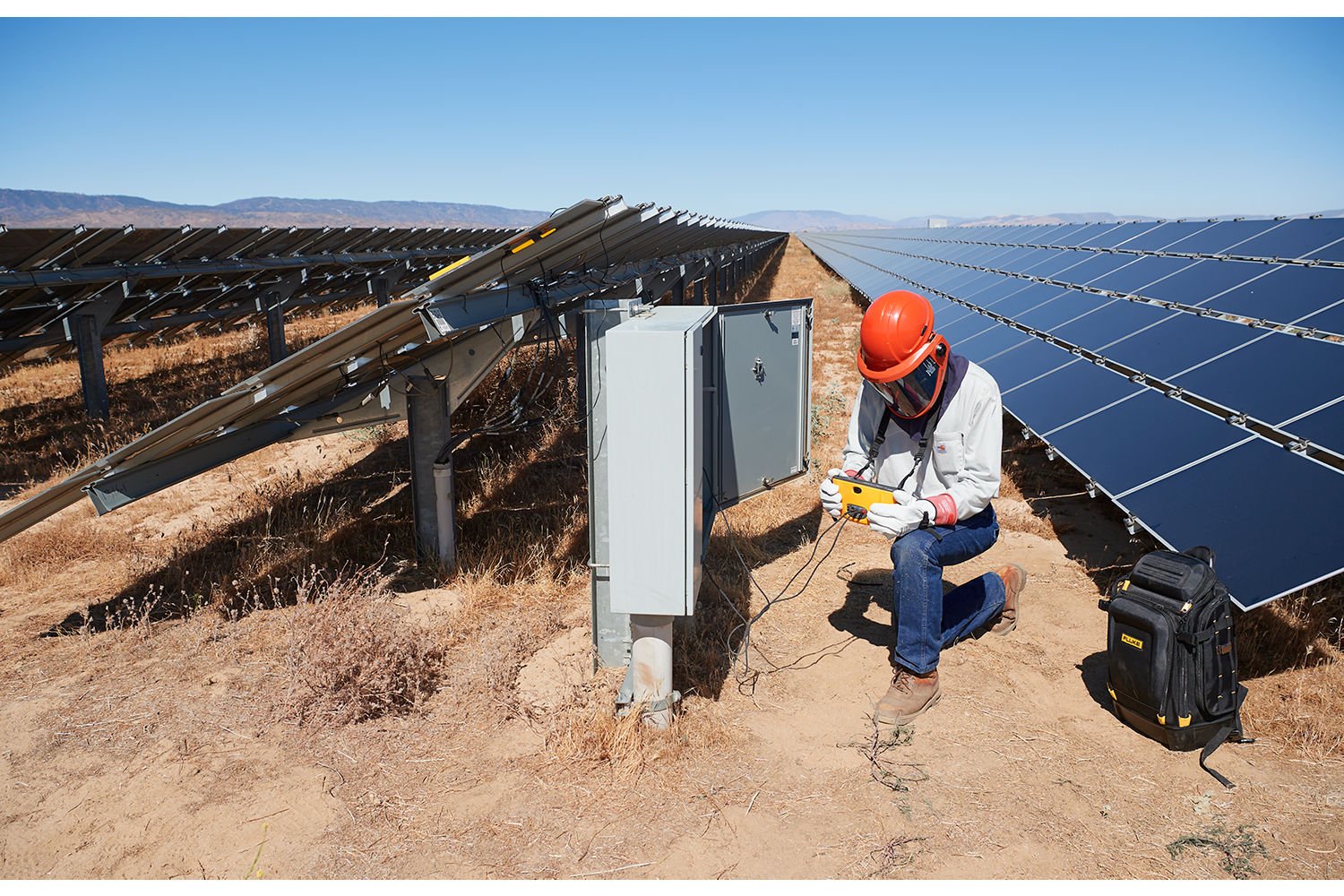 Solar technician at combiner box in PV array 1500x1000