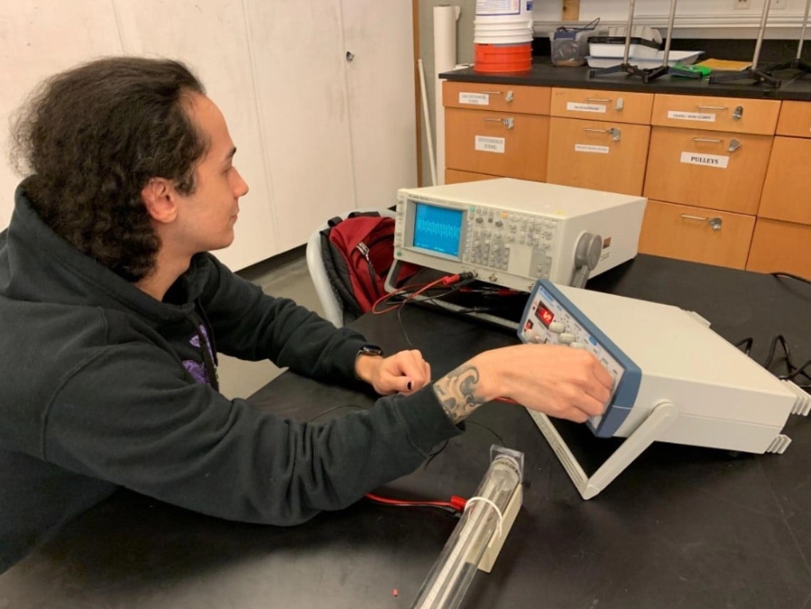 An Everett Community College physics student finding nodes of sound resonance using a Fluke oscilloscope